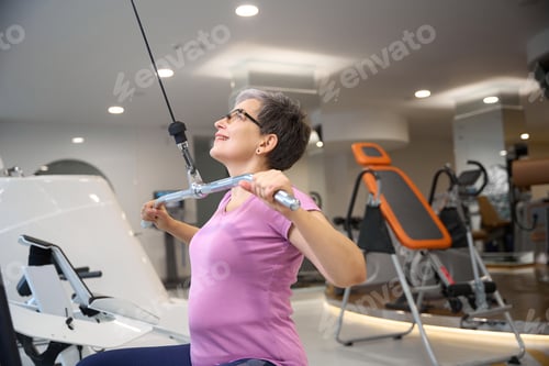 Preview: Middle aged woman wearing sportswear doing sport exercise for back in gym