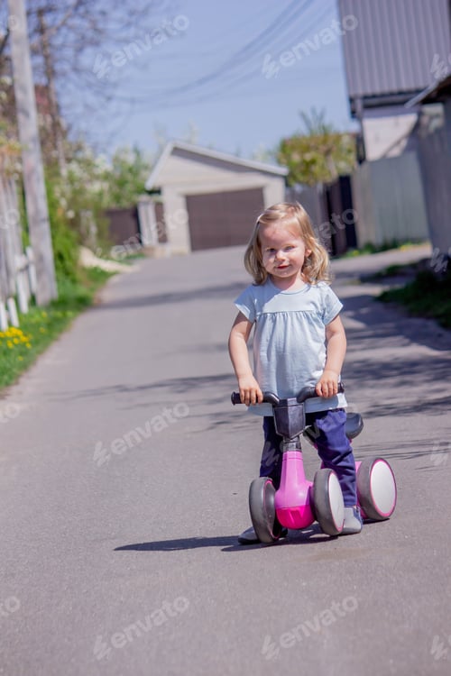 Preview: Little girl riding a balance bike. nature.