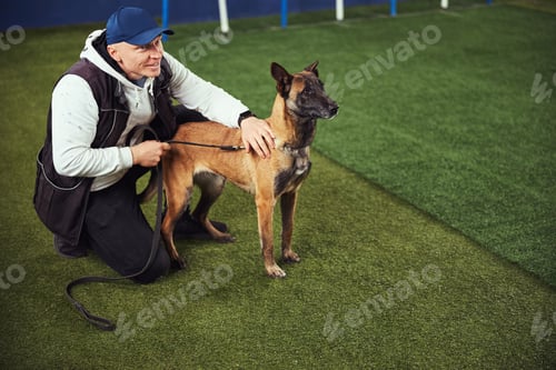 Preview: Contented trainer and a Belgian Malinois in the obedience school