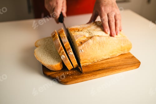Preview: Homemade sourdough bread. Woman hands cuts the bread on cutting board. Handcrafted. Wooden cutting