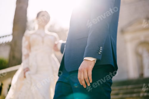 Preview: Groom gives his hand to bride going down the stone steps. Blur