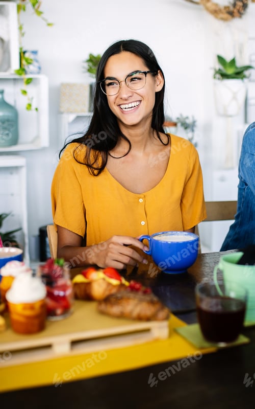 Preview: Happy young woman enjoying brunch with friends at coffee shop