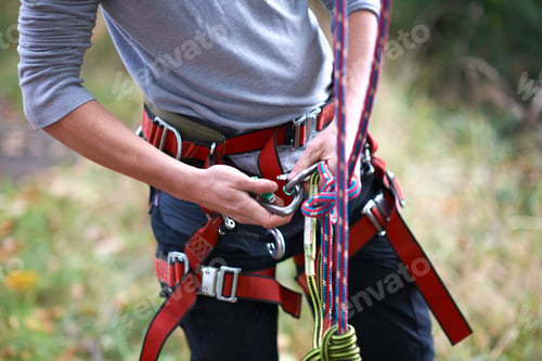 Preview: Mid section of young male trainee tree surgeon fastening safety harness