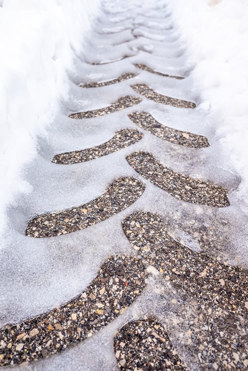Preview: Detail of the traces of a wheel on the snowy asphalt, seen from above.