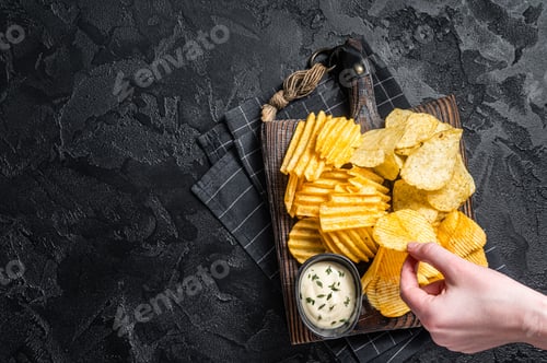 Preview: Delicious Potato chips - Crinkle, homemade, hot BBQ on a wooden board.