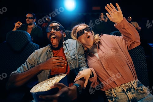 Preview: Excited couple watching movie with 3D glasses at cinema.