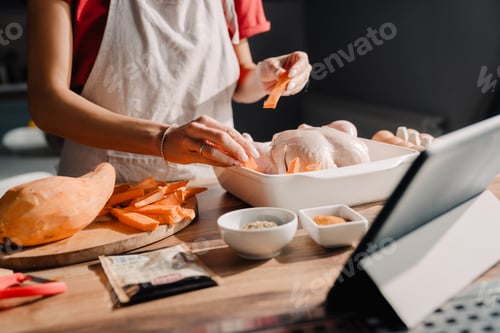 Preview: Young woman using tablet-computer while cooking in kitchen