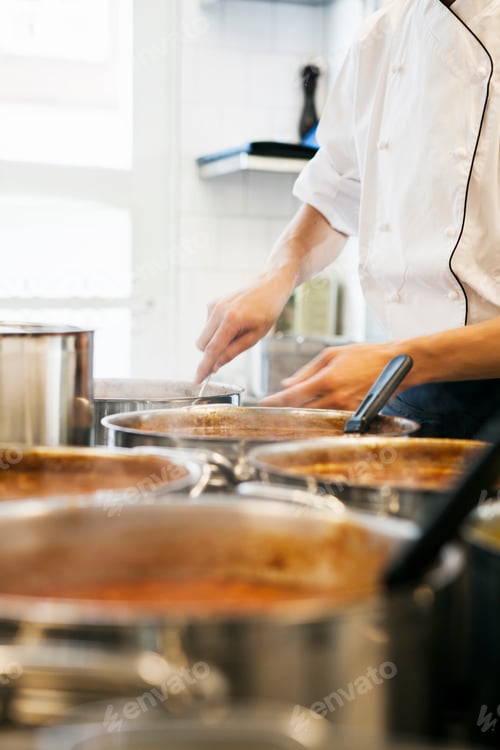 Preview: Midsection of male chef stirring gravy in utensil at commercial kitchen