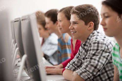 Preview: A group of young people, boys and girls, working at computer screens in class.