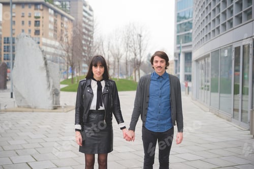 Preview: couple of young caucasian man and woman posing in the streets of the city hand in hand