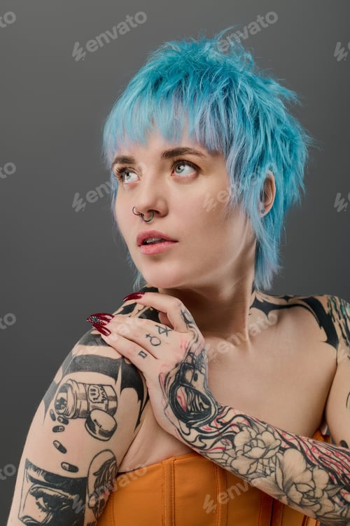 Preview: Young woman with vibrant blue hair and striking tattoos showcases unique style and confidence