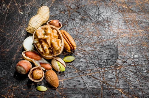 Preview: Nuts background. Assortment of different nuts with green leaves .