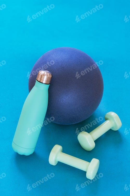 Preview: Sport ball, dumbbells and bottle with water on blue sports mat. Home training concept