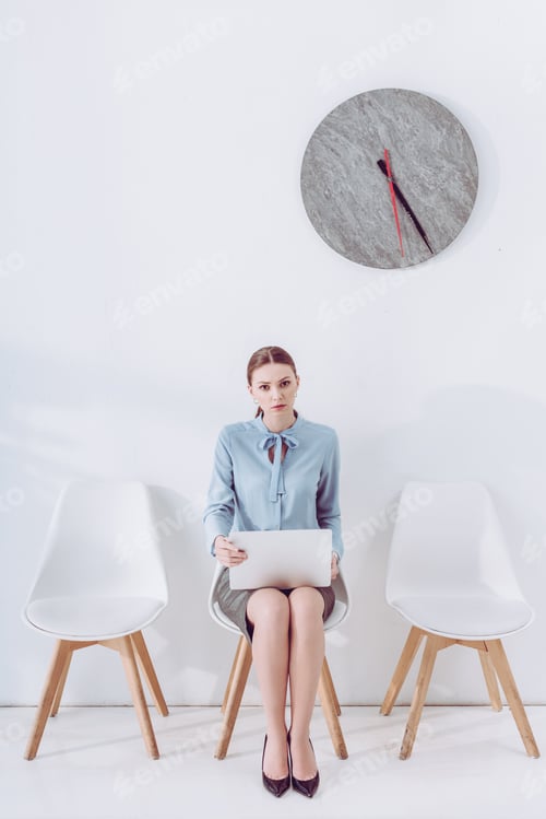 Preview: attractive employee sitting on chair with laptop while waiting job interview