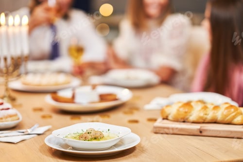 Preview: Hanukkah dinner. Family gathered around the table with traditional dishes