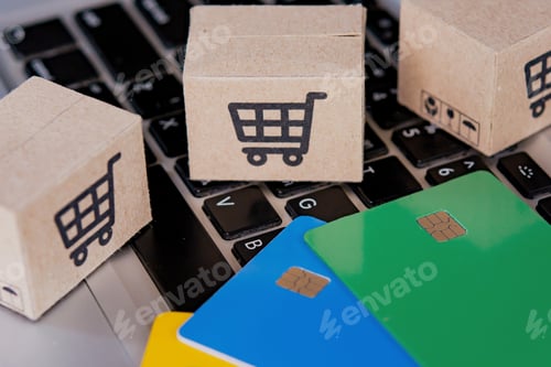 Preview: Credit card and cardboard box with a shopping cart logo on laptop keyboard.