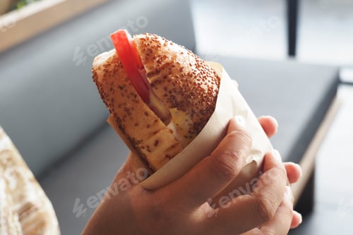 Preview: Delicious sandwich held by a hand in a casual setting