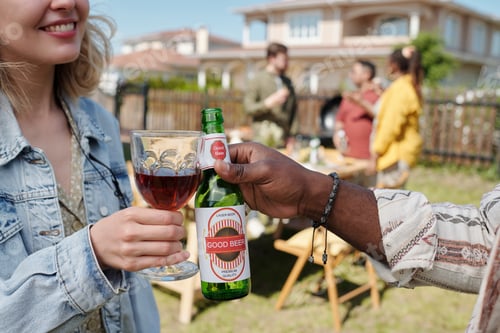 Preview: Hands of young interracial friends or couple with drinks toasting by table