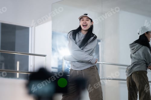 Preview: Cheerful young woman recording dance video tutorial for social media in studio