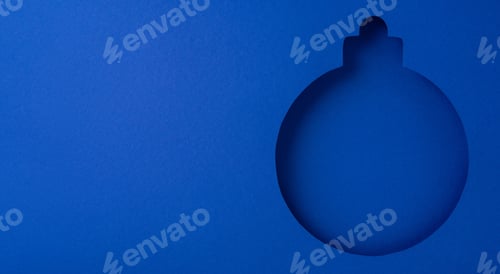 Preview: Creative blue paper cutout of a Christmas ornament shape on a blue background