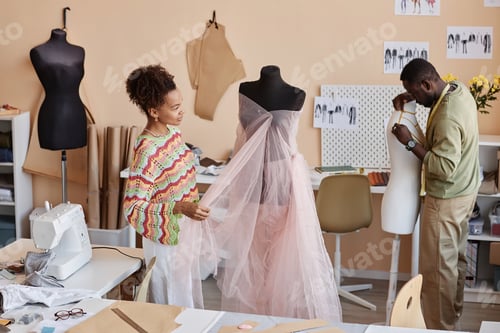 Preview: Two young colleagues standing by mannequins and creating new clothes