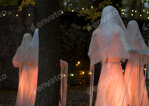 Preview: Halloween decorations, ghosts in white garments illuminated in the park