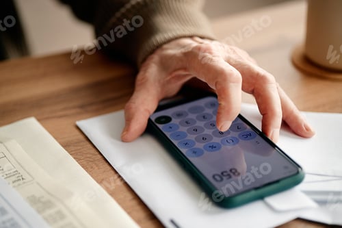Preview: Senior Woman Calculating Expenses Using Smartphone While Analyzing Bills