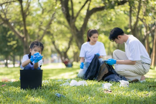Preview: Happy Asian family collecting plastic bottles at the park.