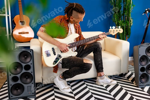 Preview: Young caucasian man with dreadlocks playing electric guitar in his room