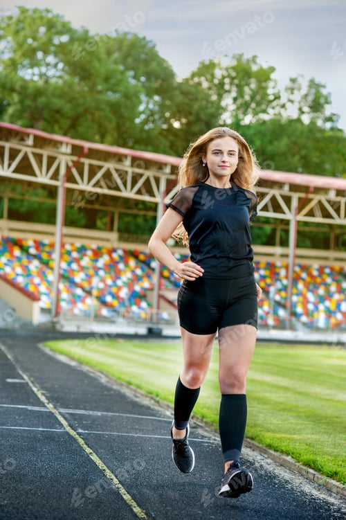 Preview: young, sporty girl running on the stadium track