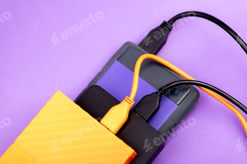 Preview: Multicolored external portable hard disk drives isolated on violet background