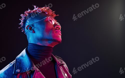 Preview: In glasses. Futuristic neon lighting. Young african american man in the studio