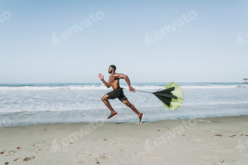 Preview: Fit man with a running parachute at the beach