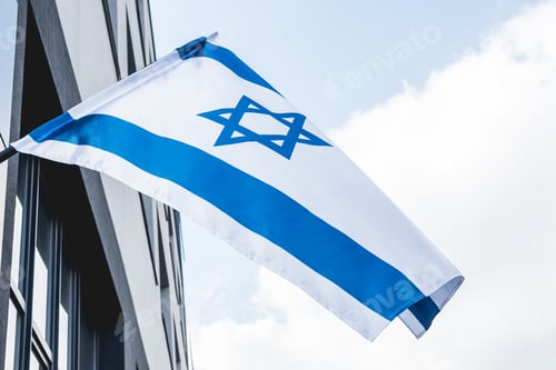 Preview: low angle view of national israel flag with star of david near building against blue sky