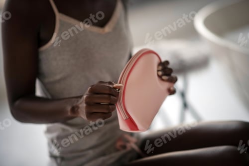 Preview: African-American woman holding her pink cosmetics bag