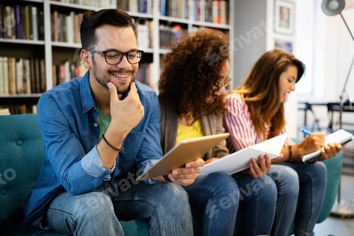 Preview: University students in cooperation at library. Group of young friends reading books