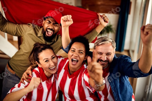 Preview: Excited multi-ethnic fans cheering for their team while watching sports match on TV at home.