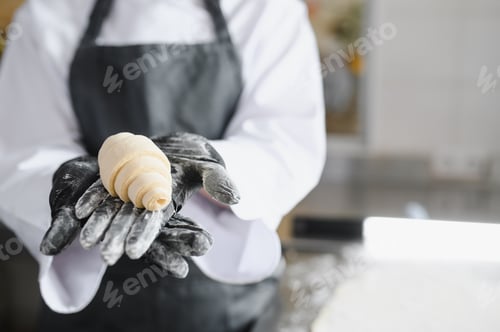 Preview: Baker showing freshly made raw croissant dough in bakery