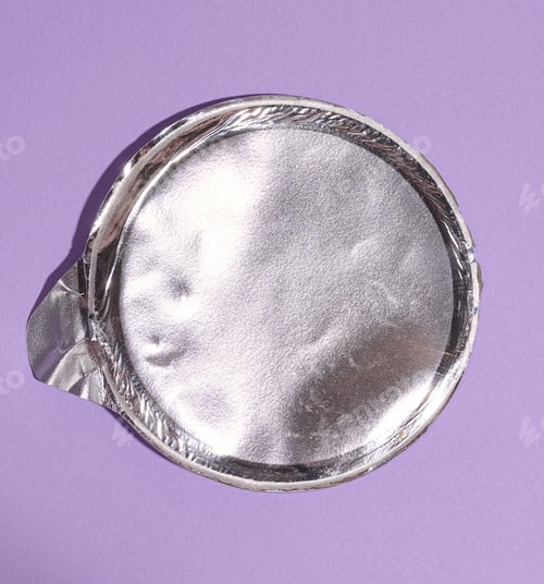 Preview: Aluminum round lid from under the package with chips on a purple background, flat lay