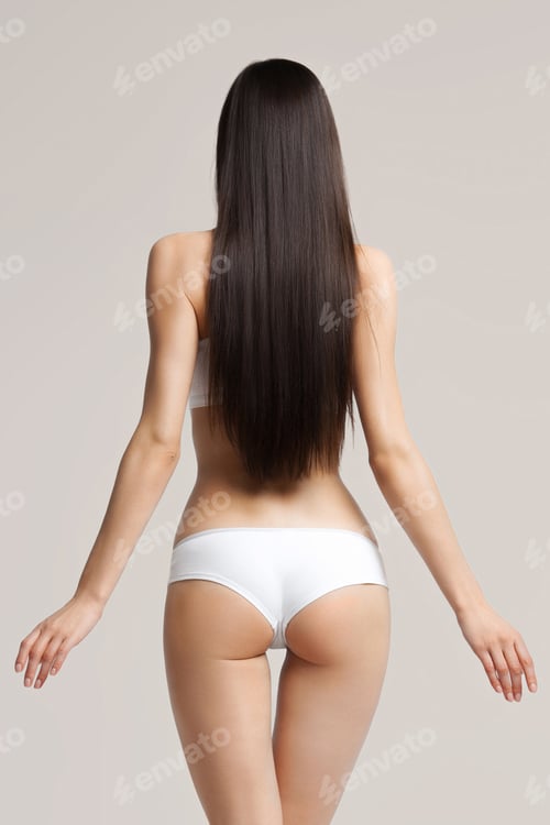 Preview: Young woman with long luxurious dark hair in white sports underwear on beige background