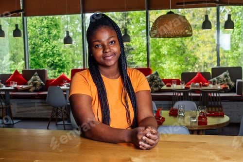 Preview: dark-skinned business woman in cafe, looking on screen of laptop standing drinking cup of coffee.