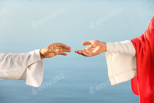 Preview: Man reaching for Jesus Christ's hand near water outdoors, closeup