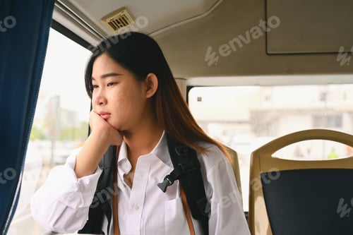 Preview: Young woman looking through looking through the window while commuting by bus