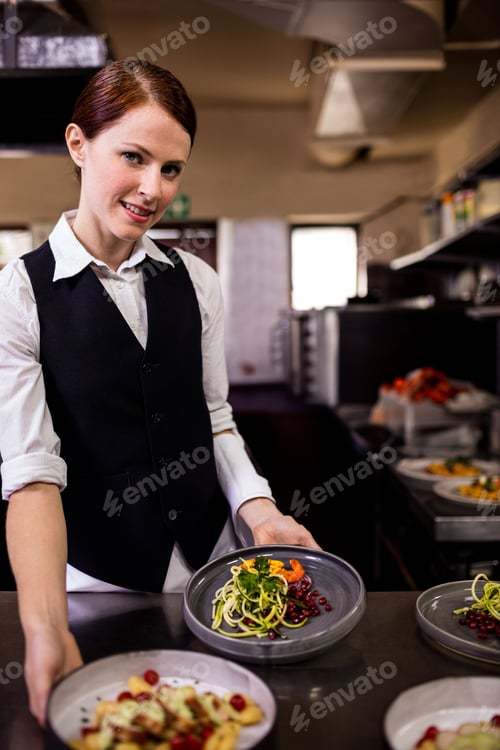 Preview: Female chef wearing uniform plating spiral veg salads with pomegranate seeds in kitchen, copy space