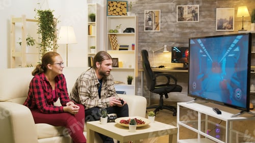 Preview: Cheerful girlfriend talking with her boyfriend while he's playing video games