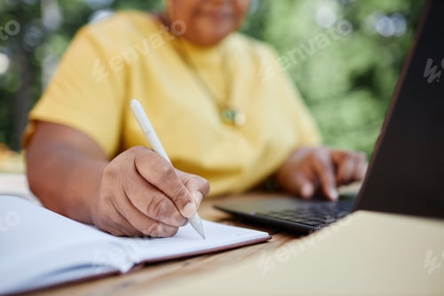 Preview: Black senior woman writing in planner working with laptop outdoors