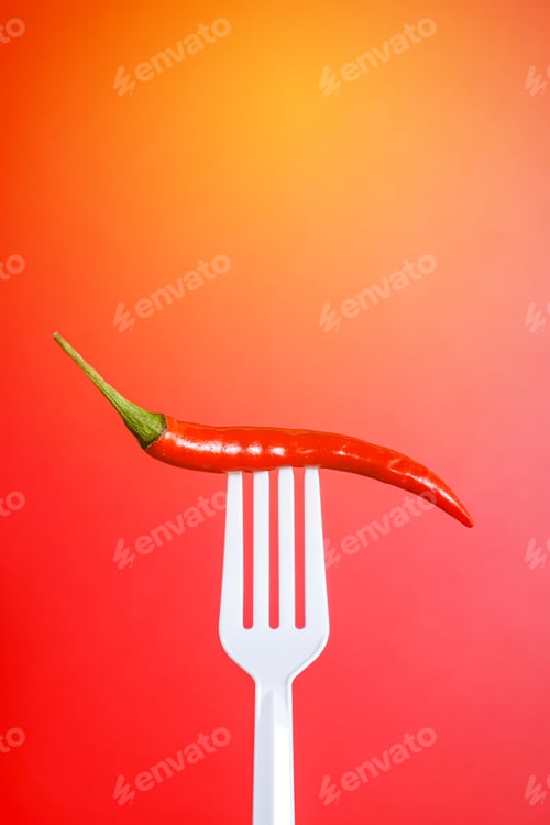Preview: Fresh red chilli on white plastic fork with red background. Hot and Spicy concept.