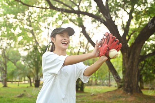 Preview: Joyful asian girl in leather glove playing baseball on green grassy lawn during summer day