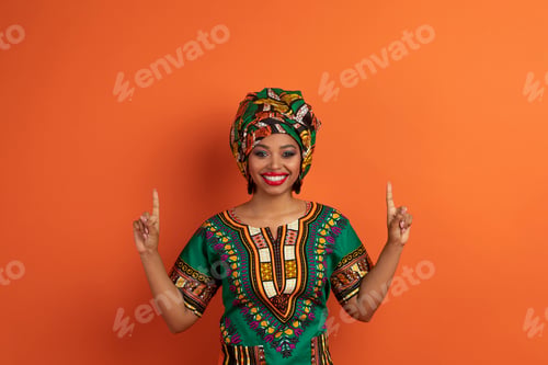 Preview: Excited young black woman in african costume showing copy space