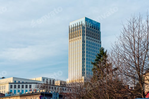 Preview: Modern skyscraper gleaming in the sunset light by Rondo Mogilskie against a clear blue